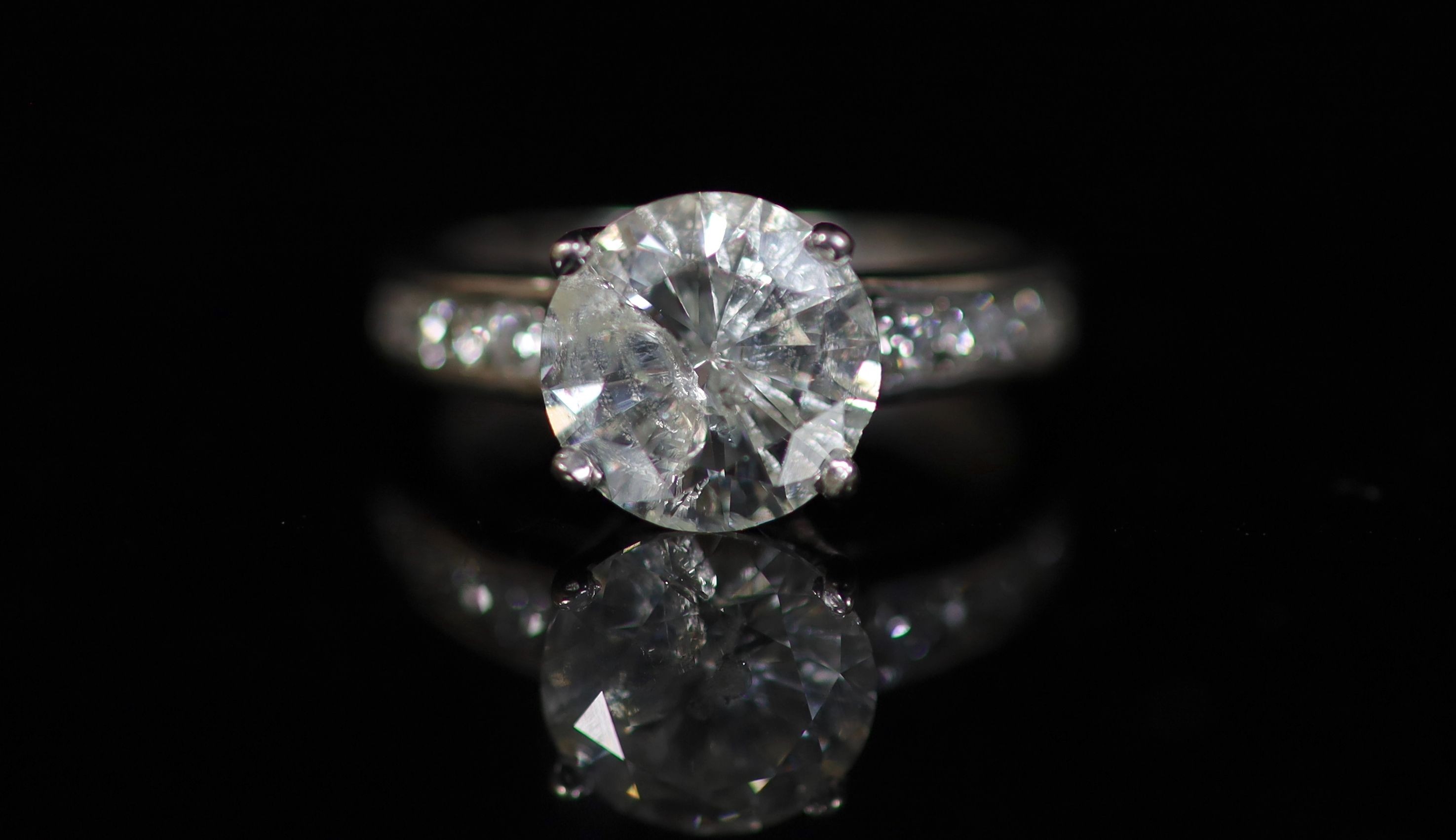 A modern white gold and single stone diamond ring, with eight stone diamond set shoulders